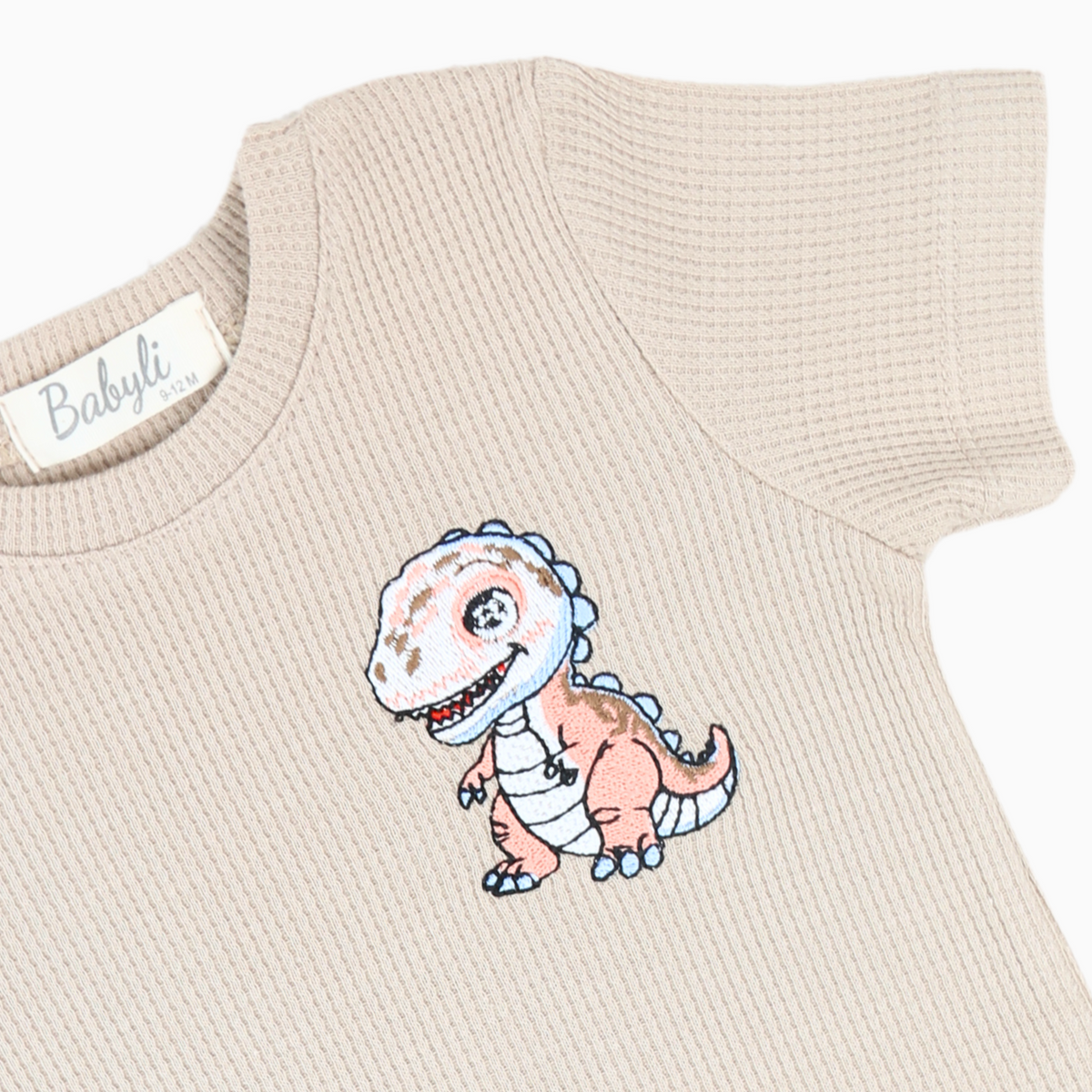Close-up of Babyli brown dinosaur embroidery on baby and toddler t-shirt and shorts set
