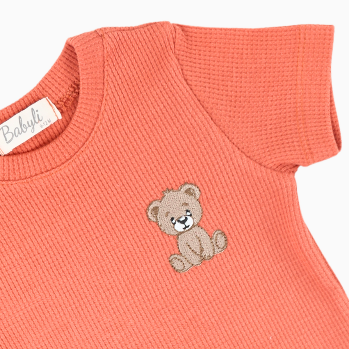 Close-up of Babyli orange teddy bear embroidery on baby and toddler t-shirt and shorts set