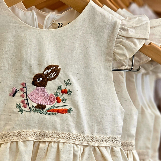 Girls sleeveless linen dress with rabbit embroidery and floral details.