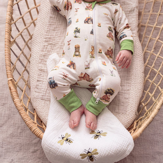 Close-up of Babyli Farmyard Zip Baby Sleepsuit showing farm animal print, tractor design and full-length zip fastening