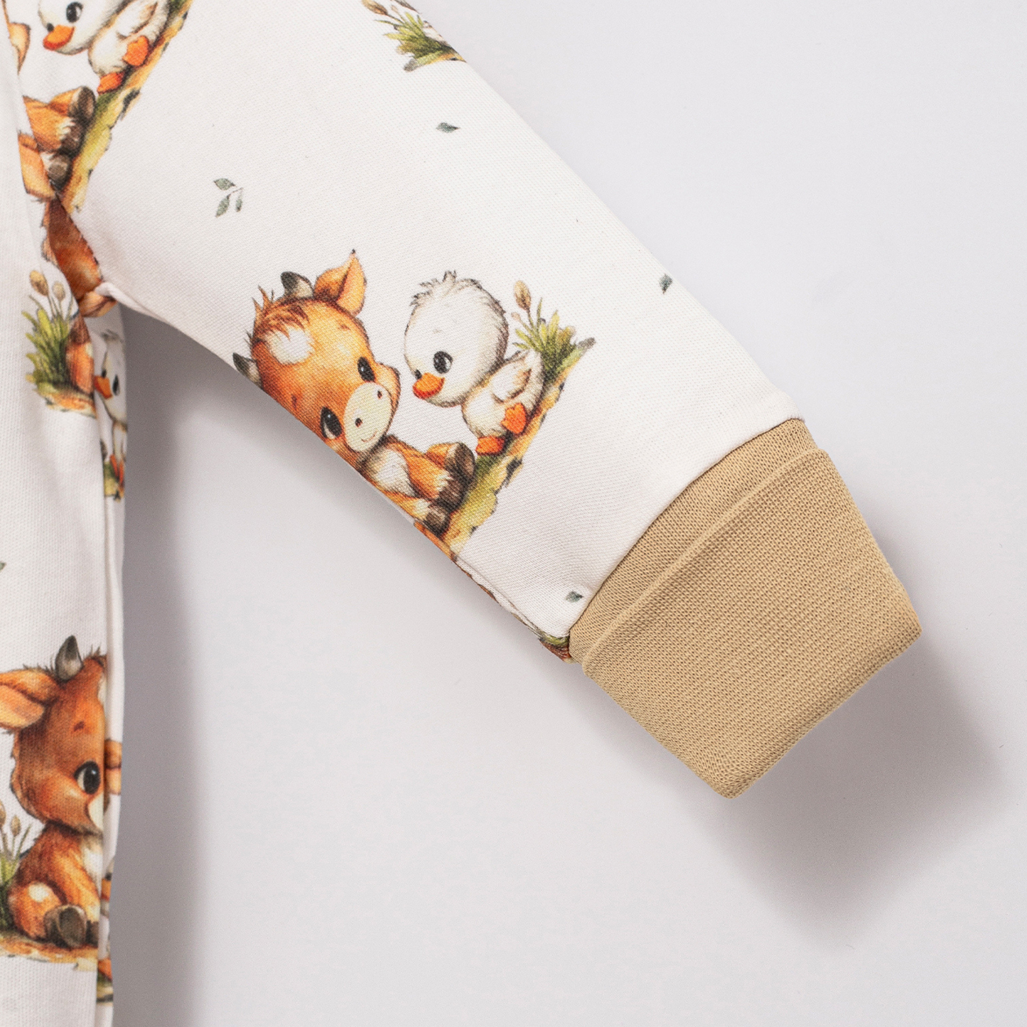 Close-up of Babyli Highland Cow Double Zip Baby Sleepsuit showing Highland cow and duck print with soft ribbed cuff detail
