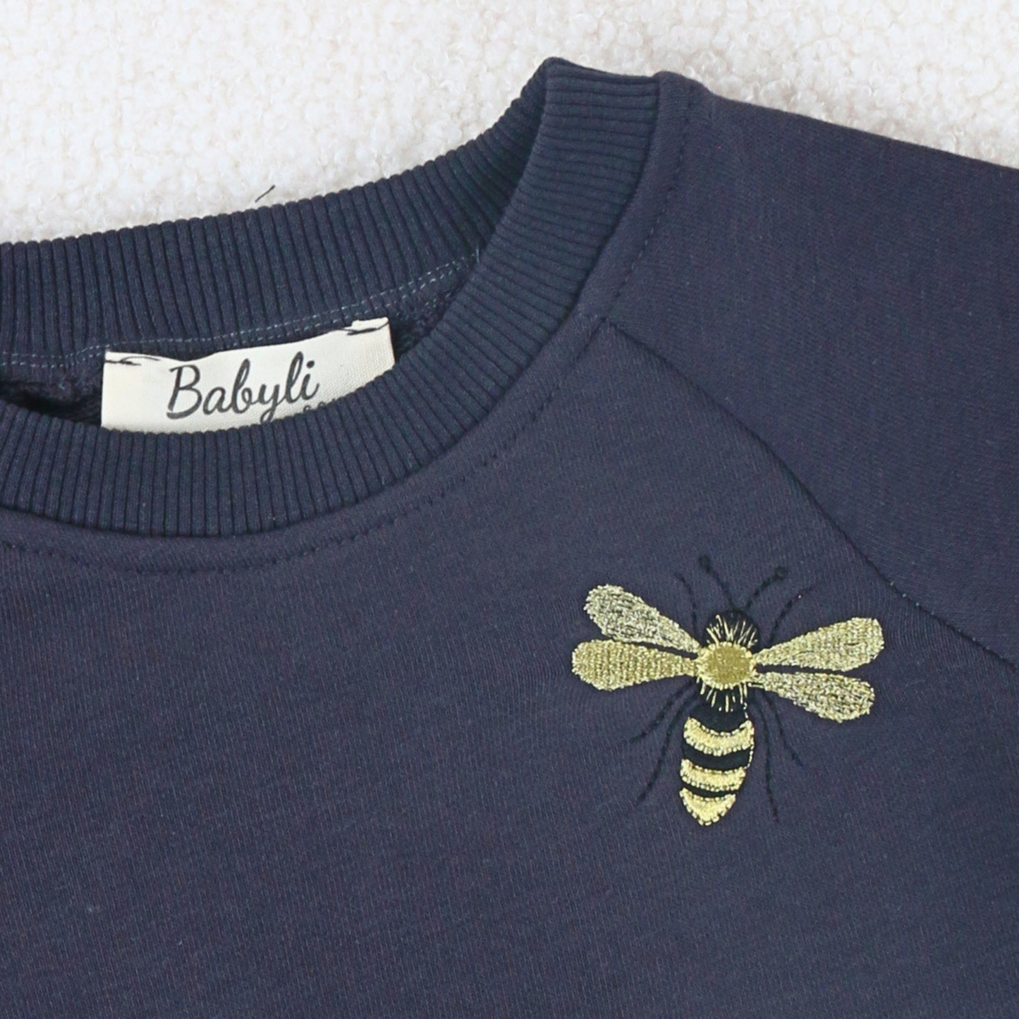 Young girl and boy wearing navy sweatshirt with bumblebee embroidery