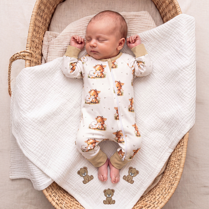 Baby wearing Babyli Highland Cow Double Zip Baby Sleepsuit while sleeping in a Moses basket