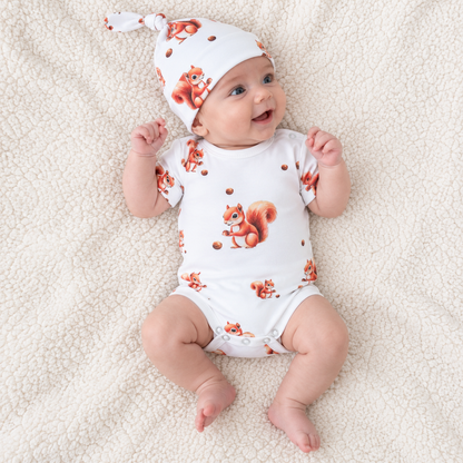 Baby lying down wearing a white cotton bodysuit with squirrel print and matching hat, Babyli baby bodysuit set
