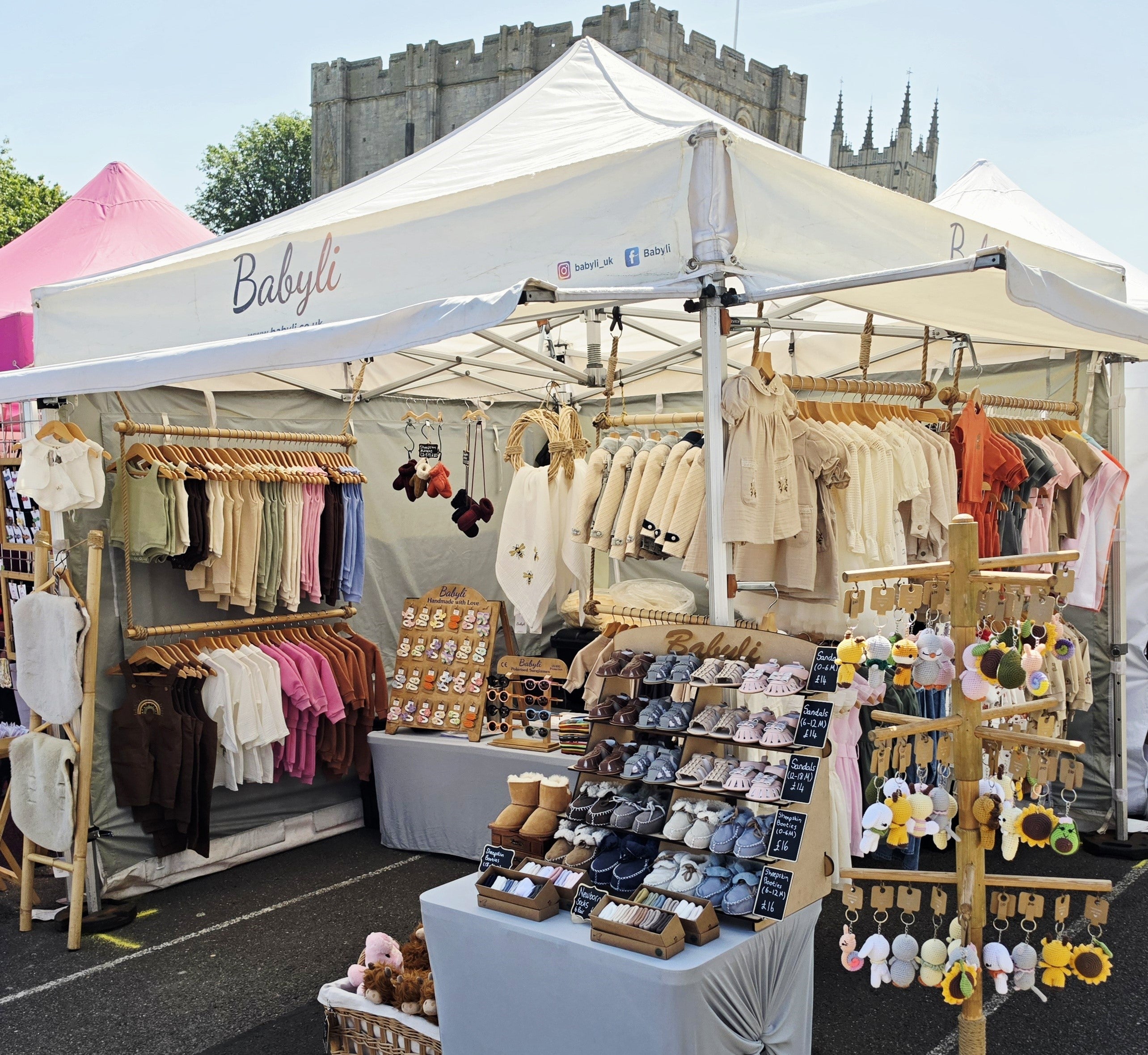 Babyli baby and toddler clothing market stall displaying soft cotton outfits, baby shoes and accessories at Bury St Edmunds outdoor market
