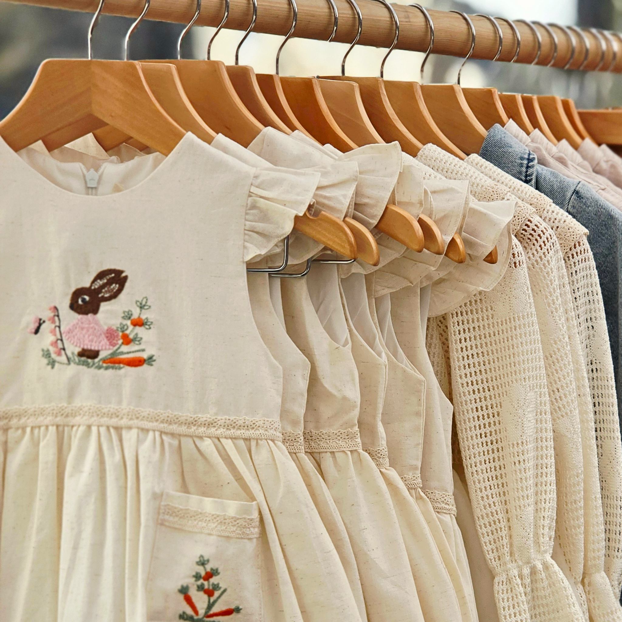 Babyli girls cream linen dresses with embroidered bunny and floral designs displayed at Bury St Edmunds market, boutique baby clothing UK