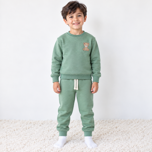 Boy wearing Babyli sage green cotton tracksuit with embroidered teddy bear