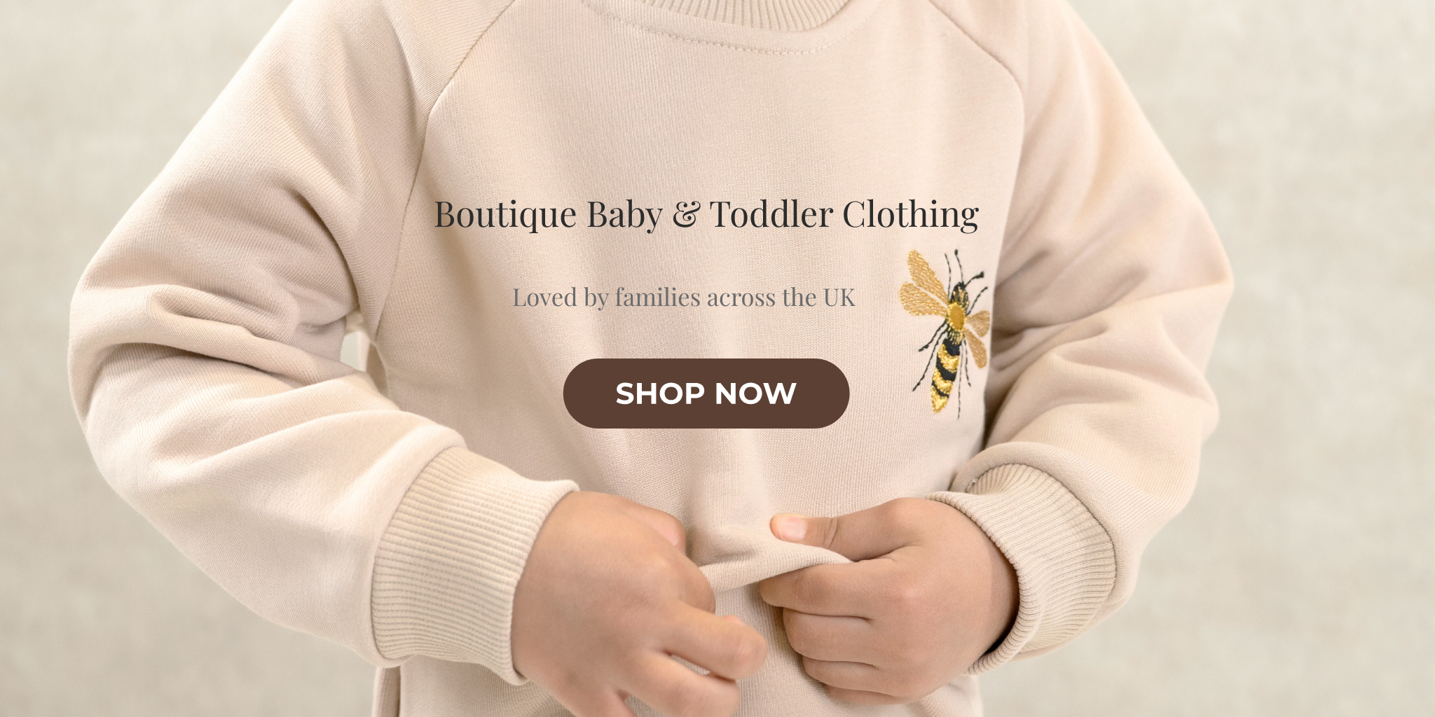 Babyli boutique baby and toddler clothing homepage banner showing child wearing cream bee embroidery sweatshirt, shop now
