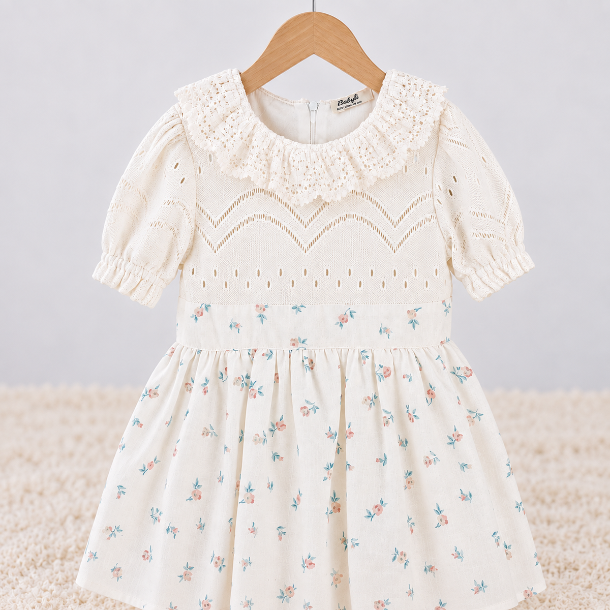 Close-up of Babyli ivory baby and toddler dress with textured knit bodice, ruffle collar and delicate floral print
