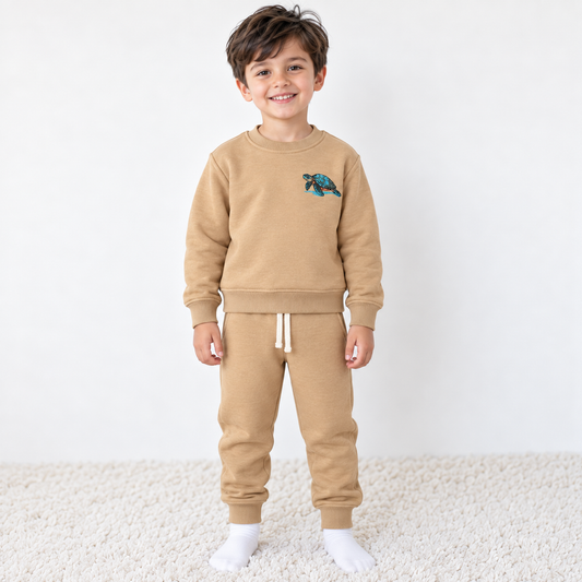 Boy wearing Babyli mustard cotton tracksuit with embroidered sea turtle