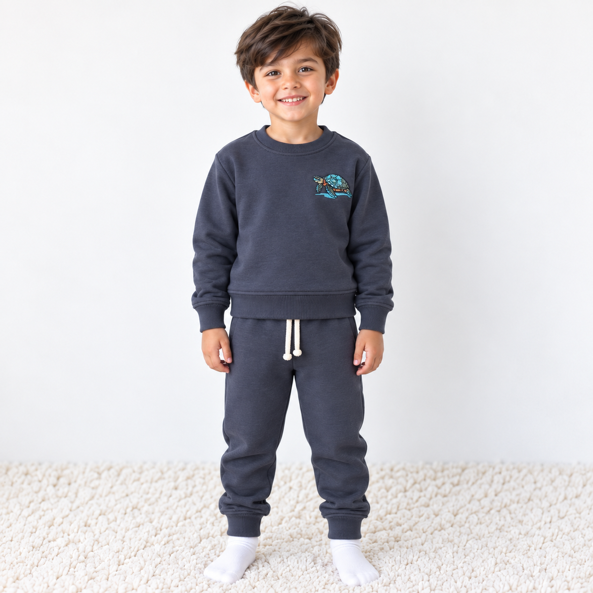 Boy wearing Babyli navy blue cotton tracksuit with embroidered sea turtle