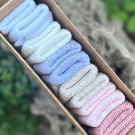 Soft newborn baby socks in pink, beige and blue colours arranged in a gift box.