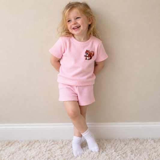 Toddler wearing Babyli pink squirrel embroidered t-shirt and shorts set, candid photo