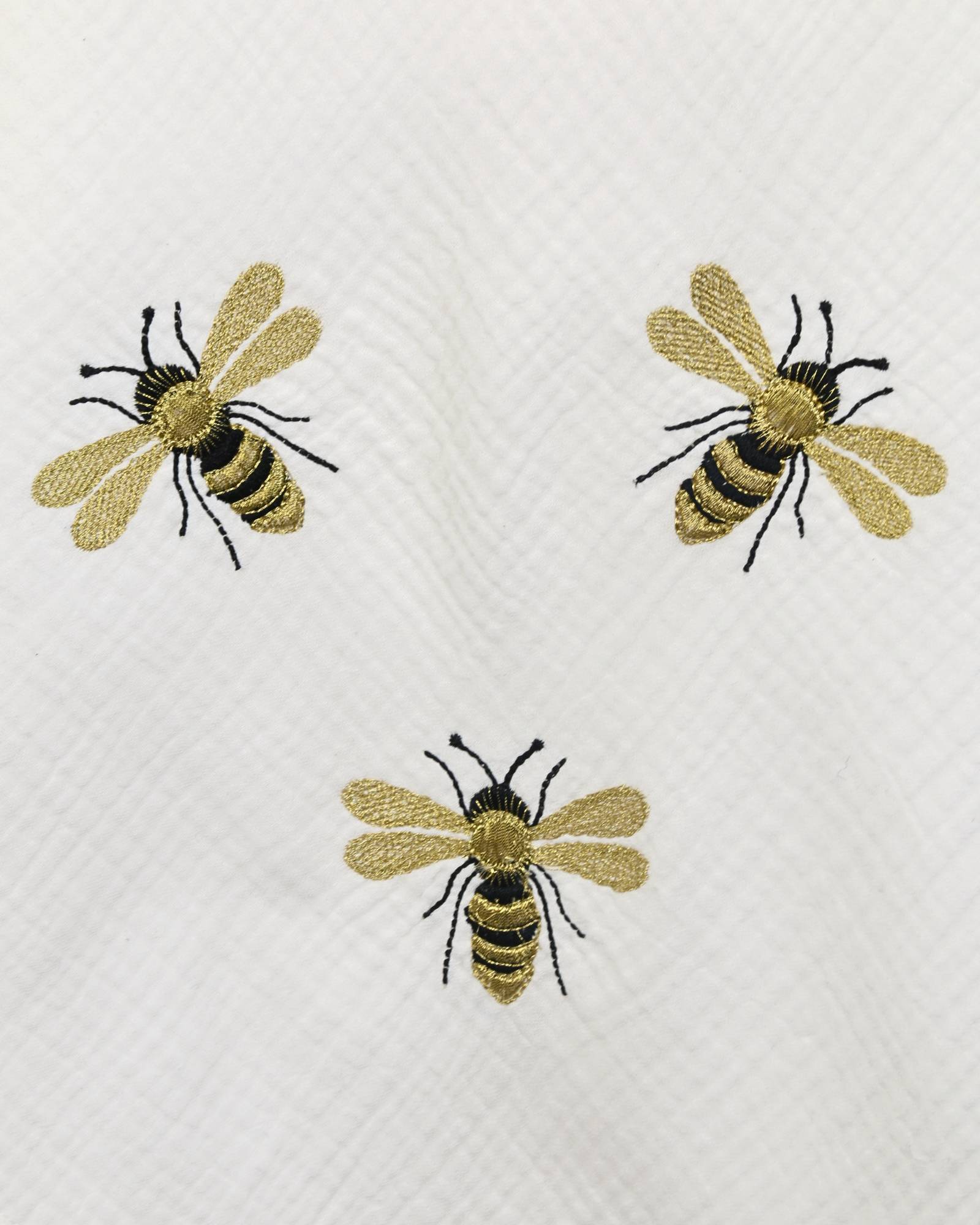 White muslin baby blanket with embroidered bee details.