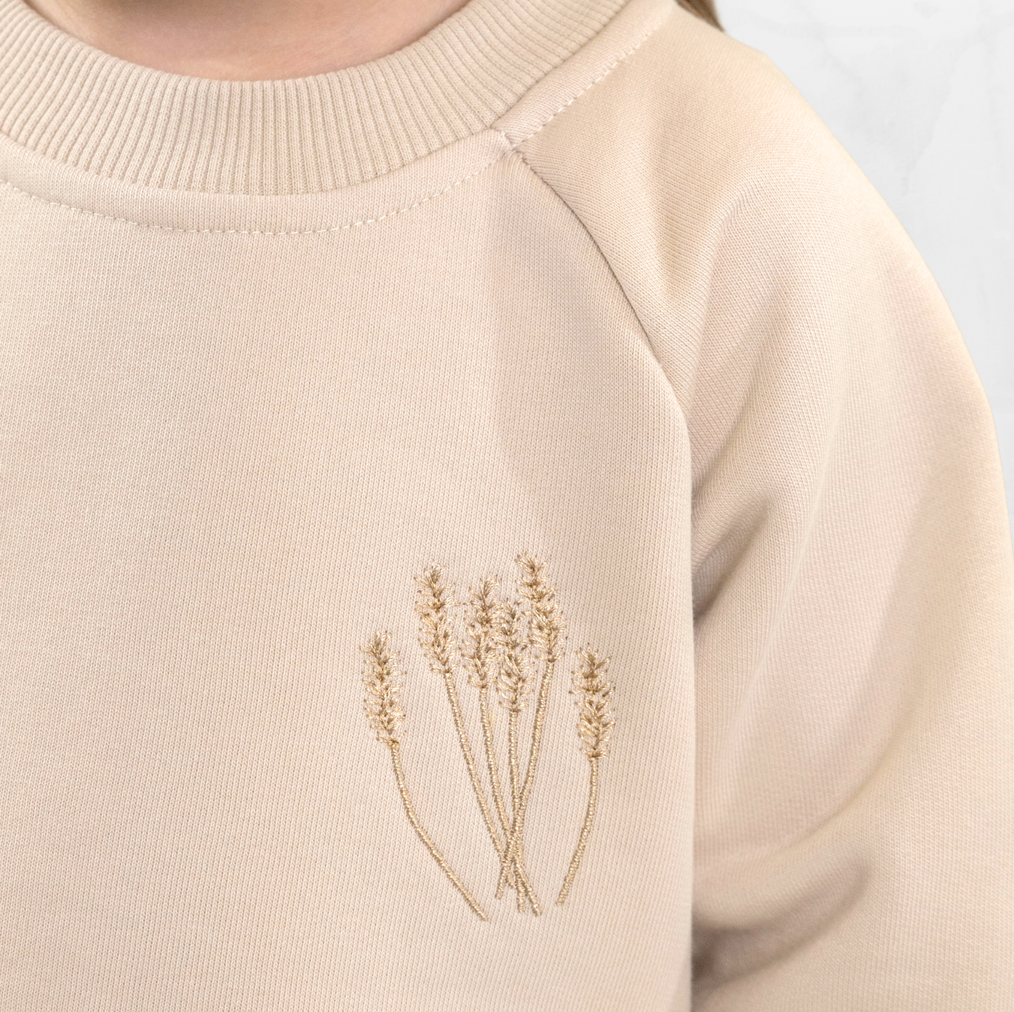 Close-up of embroidered detail on beige baby sweatshirt