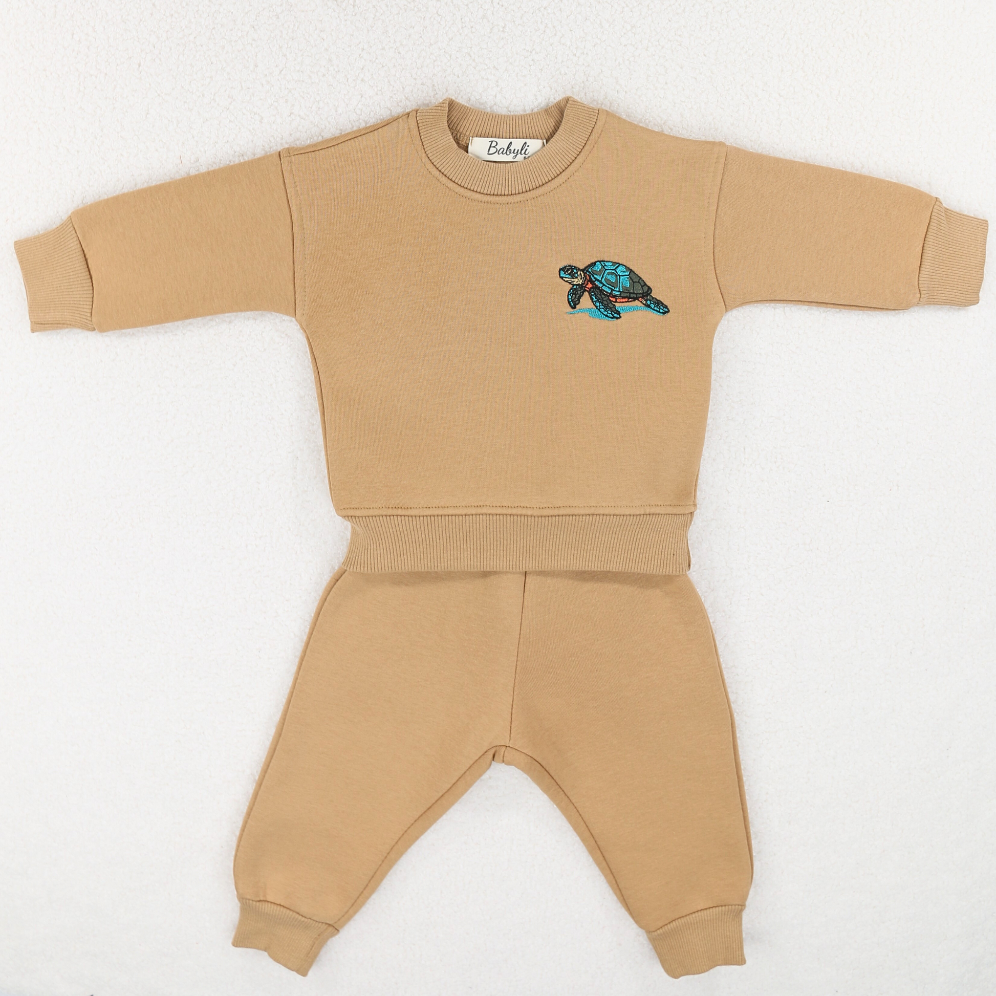 Beige baby and toddler tracksuit with embroidered turtle detail.