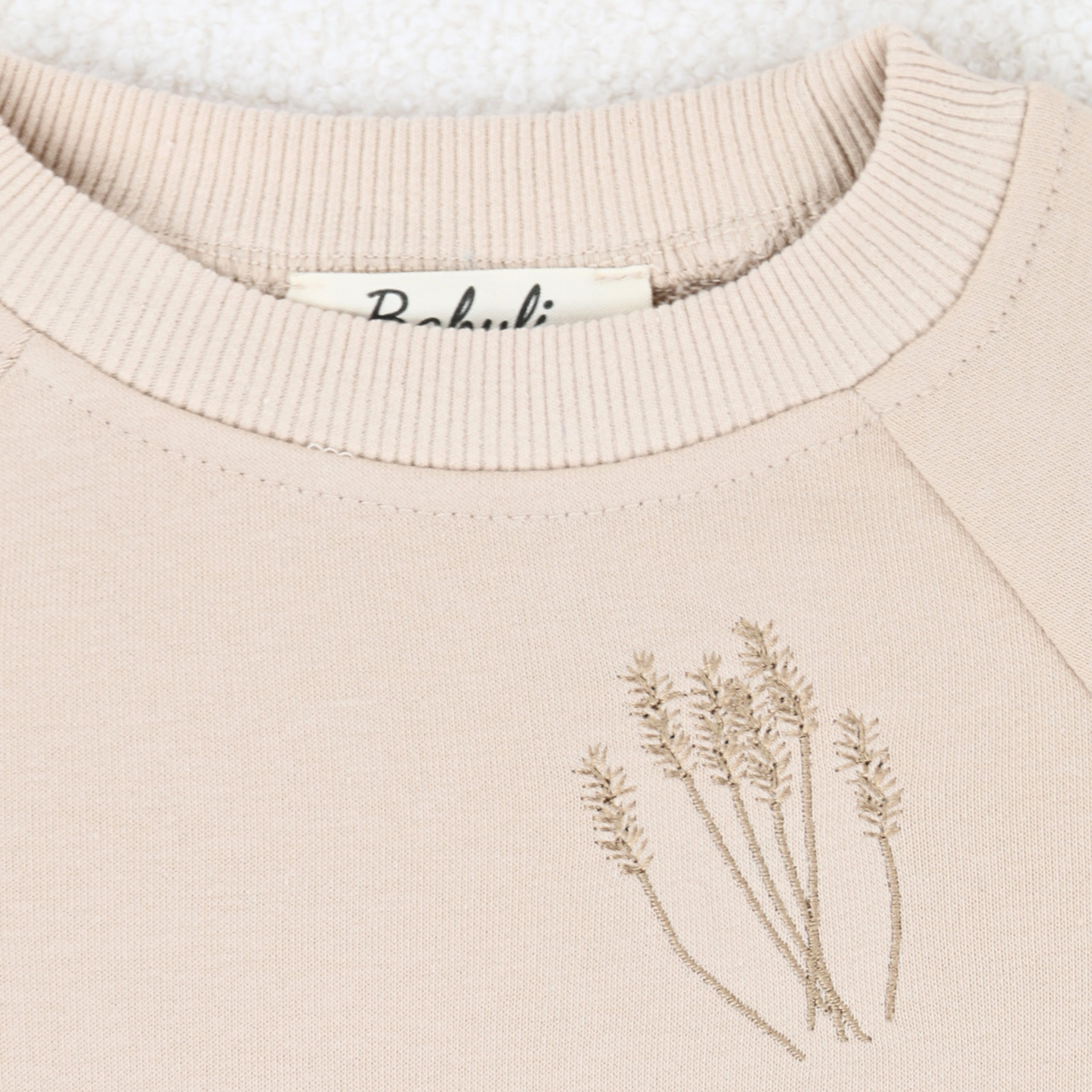 Close-up of embroidery on beige baby and toddler sweatshirt