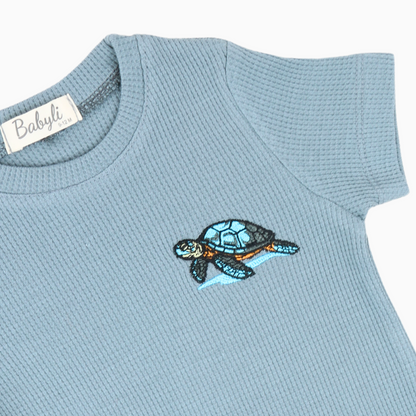 Light blue baby t-shirt and shorts set with embroidered turtle detail.