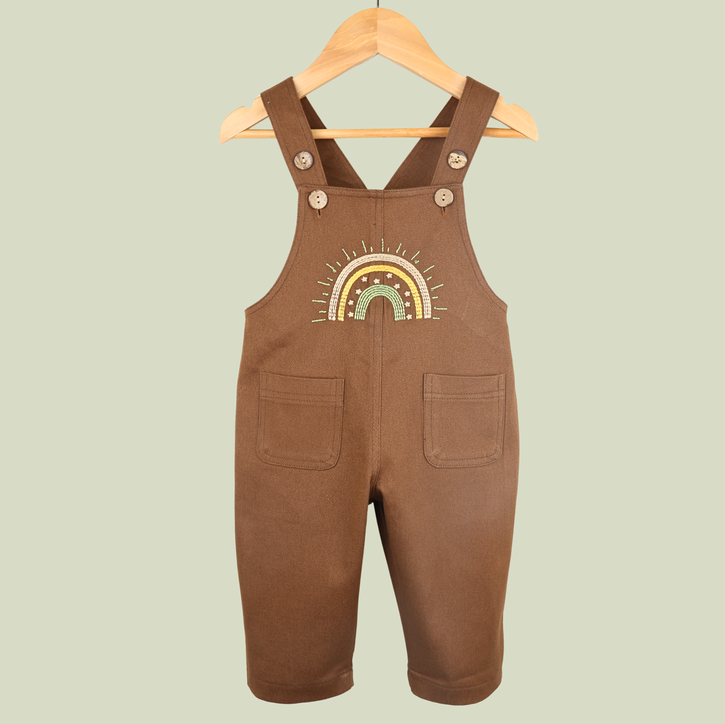 Brown baby dungarees with rainbow embroidery detail.