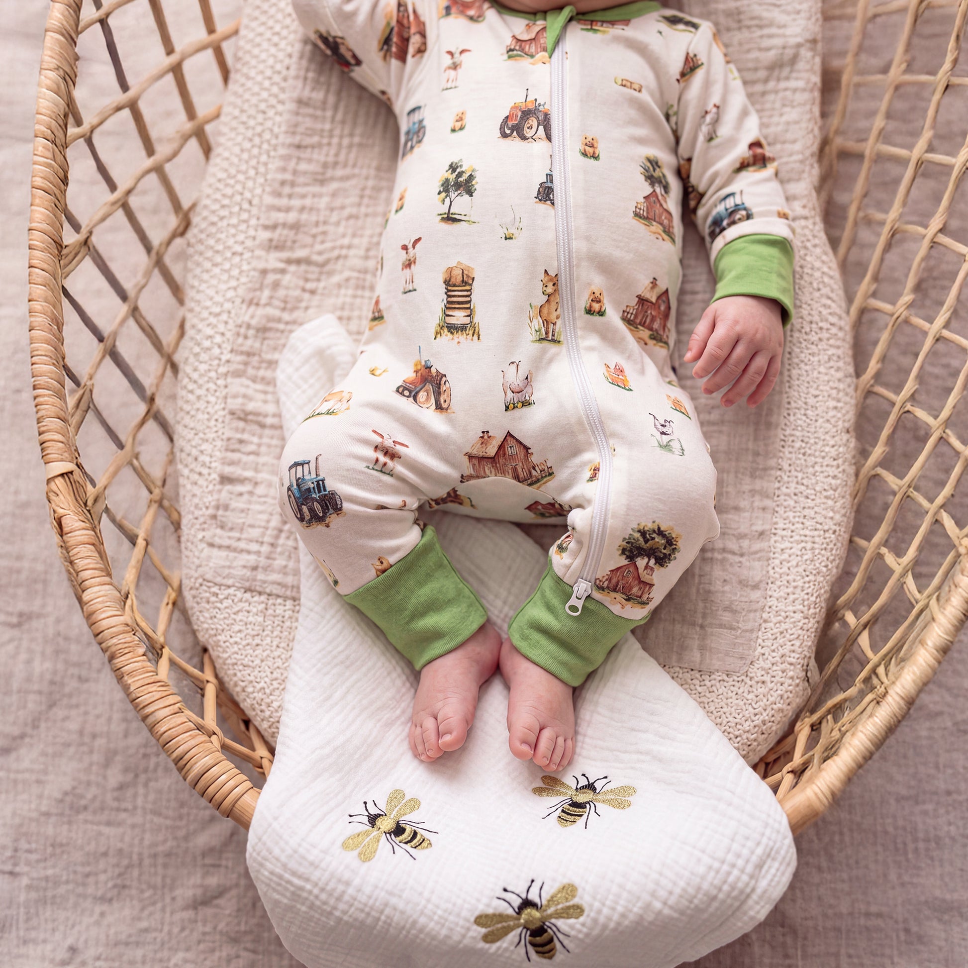 Close-up of Babyli Farmyard Zip Baby Sleepsuit showing farm animal print, tractor design and full-length zip fastening