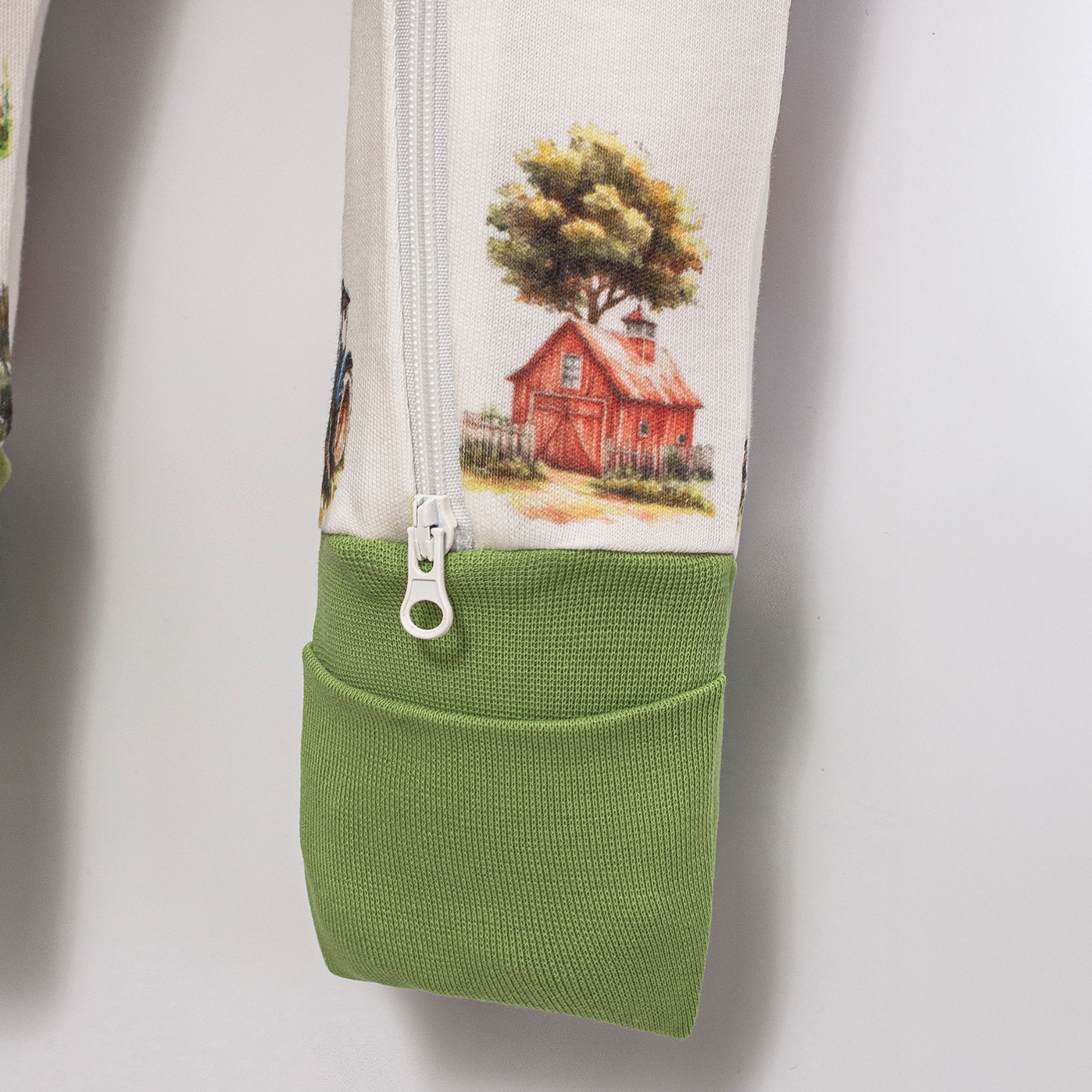 Close-up of Babyli Farmyard Double Zip Baby Sleepsuit showing two-way zip fastening, soft green ribbed cuff and farmyard print detail