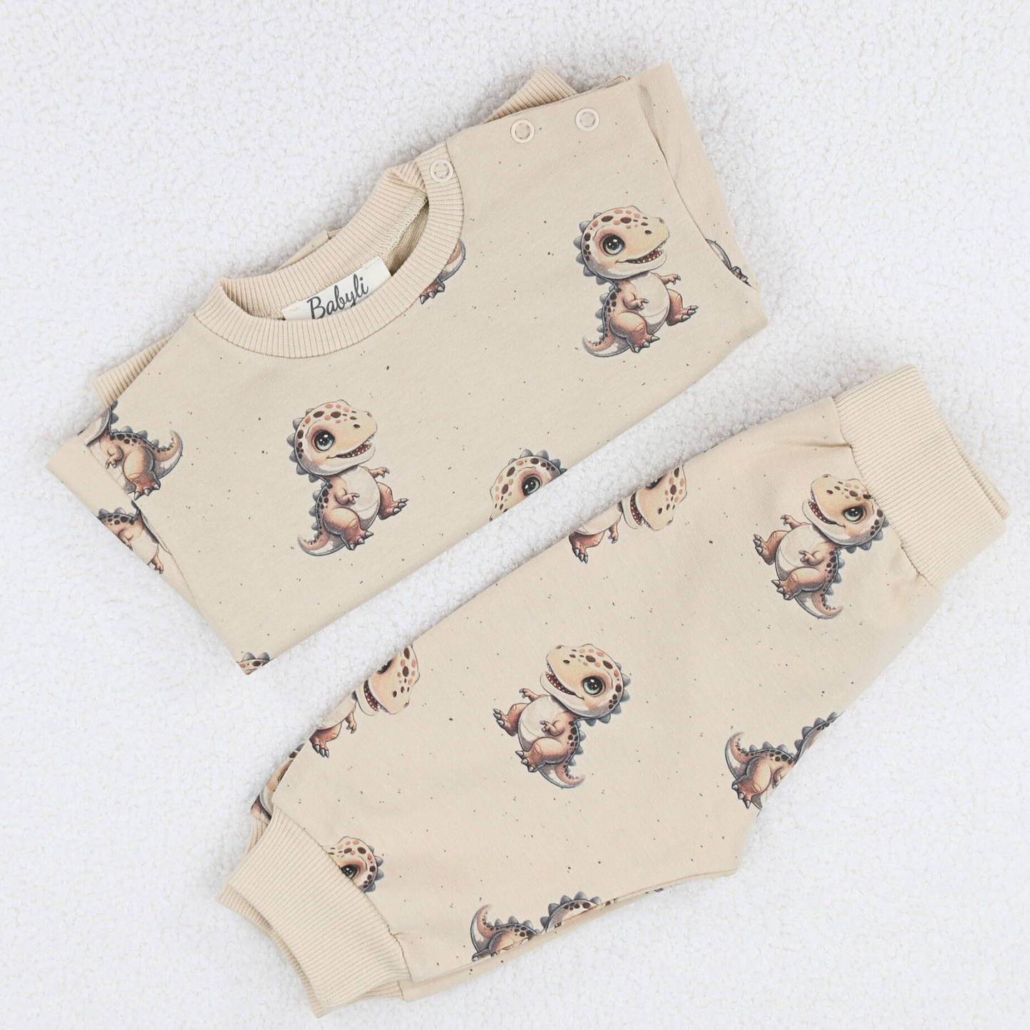 Folded cream baby two-piece set with dinosaur print