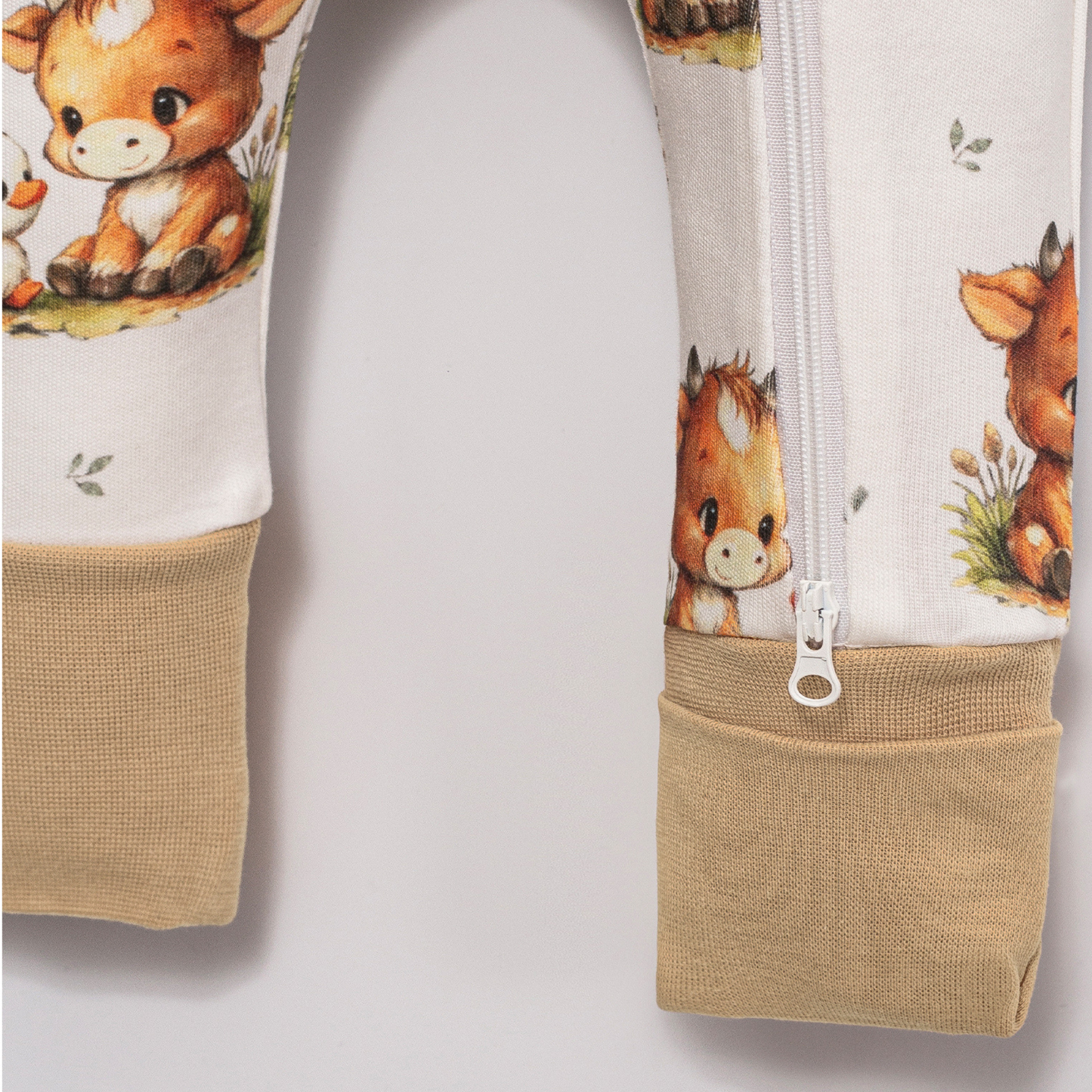 Close-up of Babyli Highland Cow Double Zip Baby Sleepsuit showing two-way zip fastening, soft ribbed cuffs and Highland cow print detail