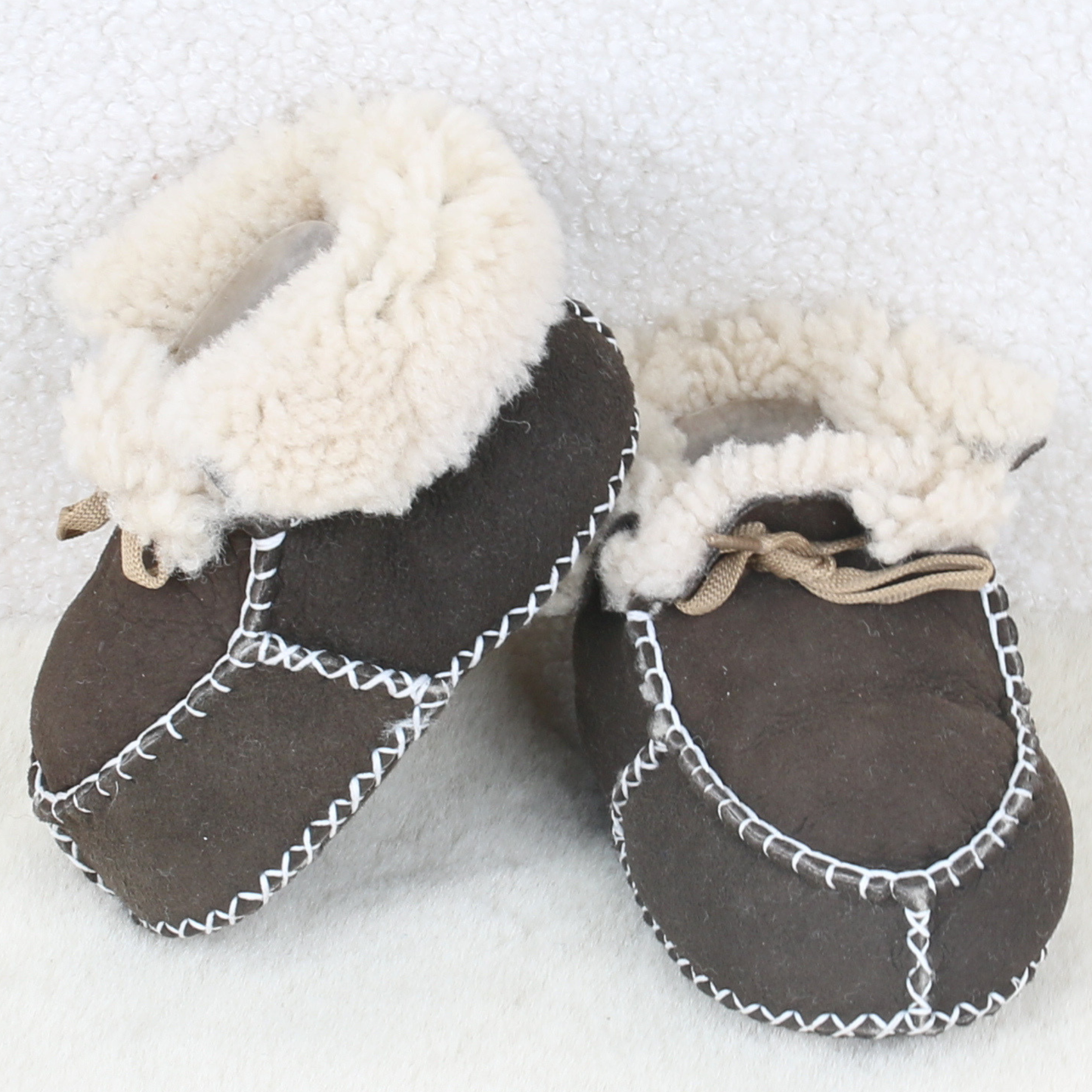 Pair of brown sheepskin baby booties with fluffy cream cuffs