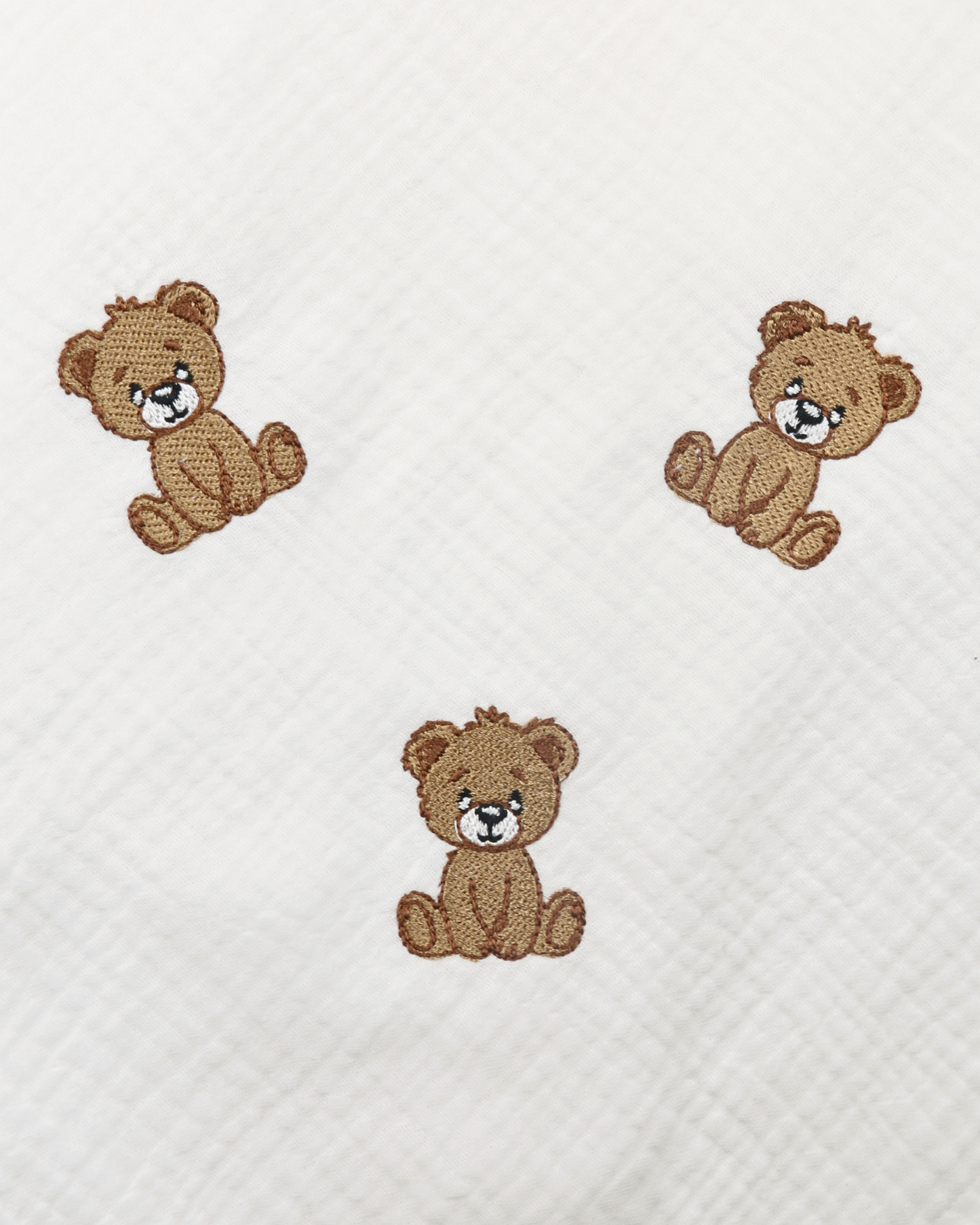 White muslin baby blanket with embroidered teddy bear details.