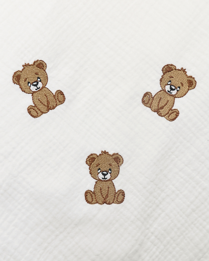 White muslin baby blanket with embroidered teddy bear details.