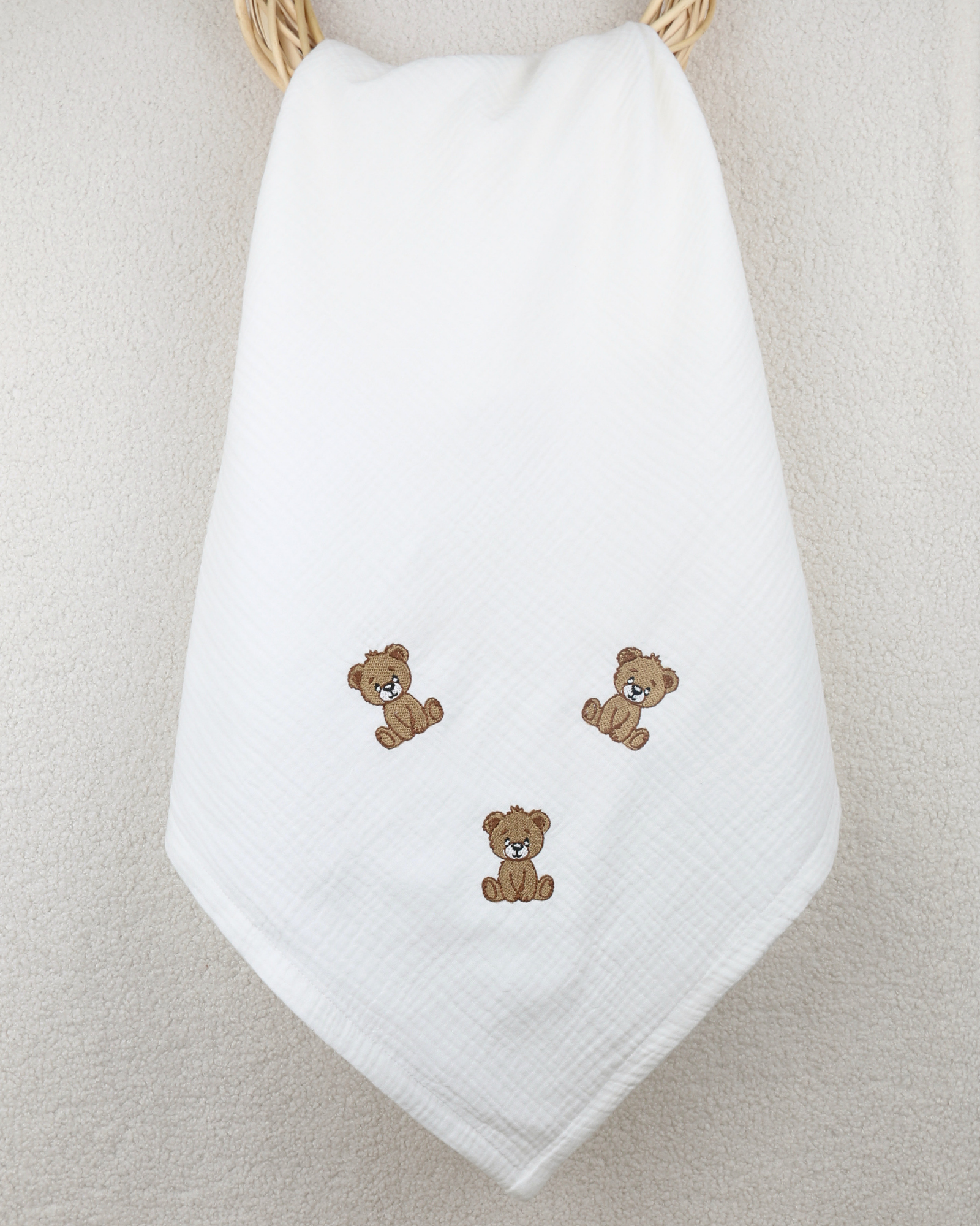White muslin baby blanket with embroidered teddy bear details.