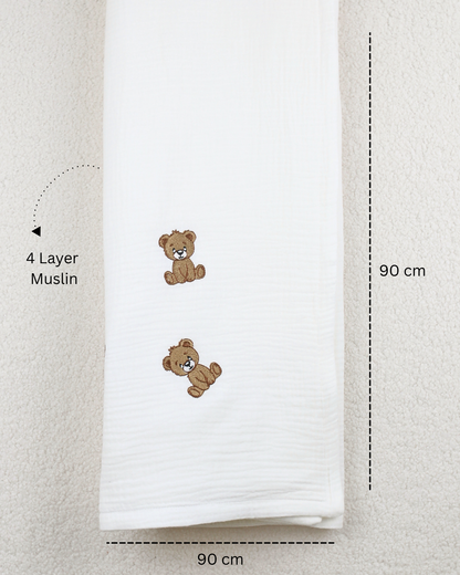 White muslin baby blanket with embroidered teddy bear details.