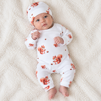 Baby lying down wearing a white cotton romper with squirrel print and matching hat, Babyli newborn romper set