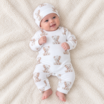 Baby lying down wearing a white cotton romper with teddy bear print and matching hat, Babyli newborn romper set
